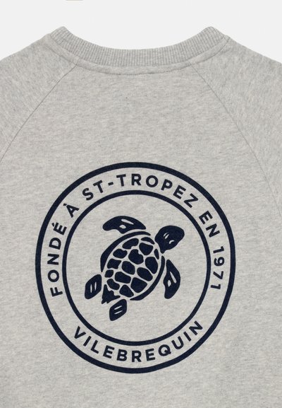 Helles graues Gewebe mit dunklem blauen Schildkrötenlogo, das in zwei Kreisen zentriert ist, und dem Text "Fondé à St-Tropez en 1971 Vilebrequin."