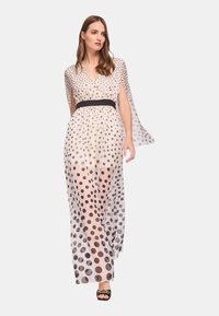 Abito lungo e trasparente con motivo a pois nero e beige, caratterizzato da scollatura a V, maniche corte a mantella e una cintura nera in vita.