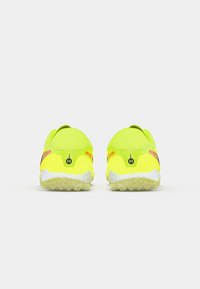 Par de zapatillas deportivas amarillas brillantes con suelas texturizadas, mostradas desde atrás sobre un fondo blanco.