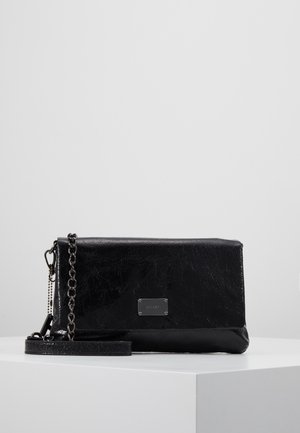 Czarna skórzana kopertówka z srebrnym łańcuszkiem i małą prostokątną metalową tabliczką z logo, na białej powierzchni.