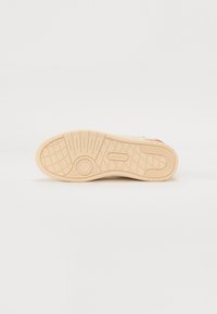 Suola della scarpa in gomma flessibile, con un motivo testurizzato, dalla forma arrotondata e di colore beige neutro, etichettata "Lacoste."