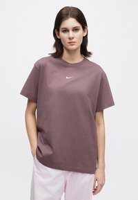 Κοντομάνικη μπλούζα με στρογγυλή λαιμόκοψη από βαμβακερό ύφασμα σε μωβ απόχρωση, με μικρό λευκό λογότυπο Nike στο στήθος. Απλός σχεδιασμός, άνετη εφαρμογή.