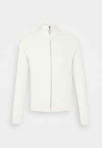 Bílá zipová mikina s vysokým límcem, ribbovaným vzorem a dlouhými rukávy. Obsahuje stříbrný zip a malé logo na hrudi.