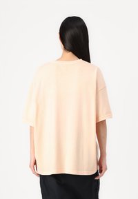 Lysrosa oversized t-shirt med korte ærmer, rund hals og blød bomuldsstruktur. Enkel, udekoreret design med en afslappet pasform.