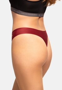 Rote Tangas mit einem glatten, minimalistischen Design. Sie verfügen über einen nahtlosen Bund, ein weiches Material und einen moderaten Schnitt.