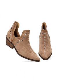 Botines de ante color canela con punteras puntiagudas, tachuelas decorativas plateadas a lo largo de los lados y tacones bajos cuadrados de madera. Textura suave y diseño curvado.