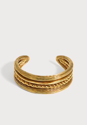 Bracelet manchette ouvert ton or avec des bandes superposées texturées et un motif corde tressée au centre, présenté sur fond blanc.