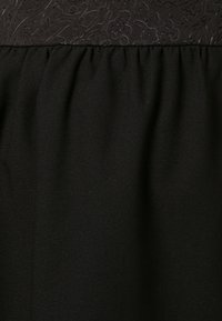 Mustat hame, jossa on teksturoitu yläpaneeli kukkakuviolla, kerätty vyötärölle virtaavaa siluettia varten. Pehmeä kangas, elegantti ilme.