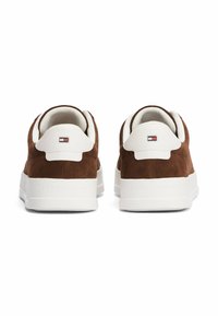 Sneaker in suede marrone con suola in gomma bianca e dettagli in bianco sul tallone. Presenta un logo sul tallone e dettagli di cucitura sulla parte superiore.