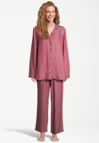 Röd- och vitrandig pyjamas i mjukt tyg, med en knäppskjorta med lång ärm och lösa, hel längd byxor.
