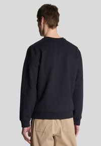 Felpa blu navy realizzata in morbido tessuto, con collo rotondo, polsini a costine e vestibilità standard, caratterizzata da cuciture minime e senza loghi visibili.