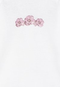 Weißer Stoff mit einem gestickten Design von drei rosa Blumen mit detaillierten Blütenblättern und zentralen Highlights, horizontal angeordnet.