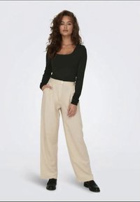 Long-sleeve black top with a square neckline paired with beige high-waisted wide-leg trousers. Black shoes complete the outfit.