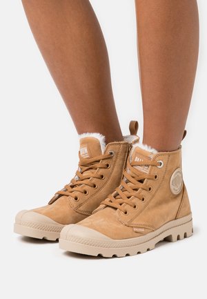 Brune lær ankle boots med teksturfinish, snøring foran, kremfarget gummitåhette og myk fôr ved kragen. Merkevarelogo på siden.