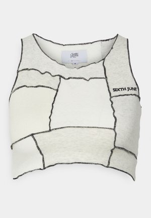 Balta apgriezta blūze, kas izgatavota no mīkstas auduma ar kontrastējošu melnu šuvju. Tai ir plecu šuvju dizains un apaļa apkakle ar birku.