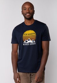 Donkerblauwe katoenen t-shirt met een grafische print van bergen en een zon, tekst in het Duits, korte mouwen en een ronde hals ontwerp.