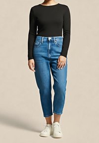 Černý dlouhý rukáv spojený s vysokými světle modrými džíny a bílými teniskami. Džíny mají rovný střih a mírně vybledlou barvu.