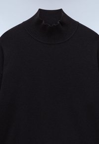 Pull noir côtelé à col cheminée avec manches longues et tissu doux légèrement texturé.