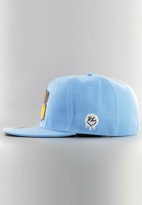 Vaaleansininen snapback-lippis, jossa on litteä lippa, etupuolella brodeeratut grafiikat ja sivussa pieni logotarra.