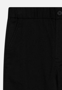 Pantaloni neri con una texture liscia, dotati di una tasca laterale e chiusura con bottone. Vestibilità sartoriale con design classico e senza motivi visibili.