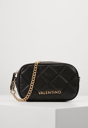Black quilted leather crossbody bag with gold hardware, featuring a chain strap and embossed brand name on the front, rectangular shape.