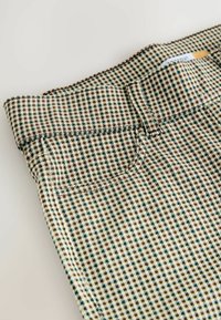 Pantaloni in misto cotone con un motivo a scacchi in beige, marrone e verde. Presentano una vita e una tasca frontale.