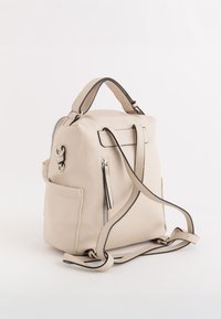 Mochila de cuero beige con un acabado texturizado, correas de hombro ajustables, asa superior, bolsillo lateral y un compartimento frontal con cremallera.