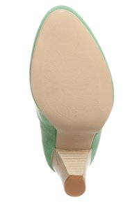 Chaussure à talon haut en daim vert avec une semelle beige texturée et un talon étroit et profilé. Motif floral en relief sur la semelle.