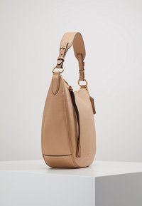 Beige leather handbag with a rounded shape, featuring a zip closure and adjustable strap. Gold-tone hardware accents add detail.