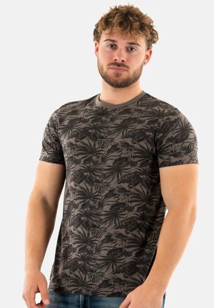 Camiseta de manga corta en gris oscuro con un patrón de hojas tropicales negras, hecha de una suave tela con un cuello redondo y un pequeño parche con logo en la manga.