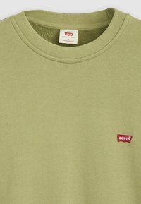 Camiseta de algodón verde con cuello redondo acanalado y pequeño parche de logo rojo de Levi's. Tejido texturizado y suave en un diseño de corte estándar.
