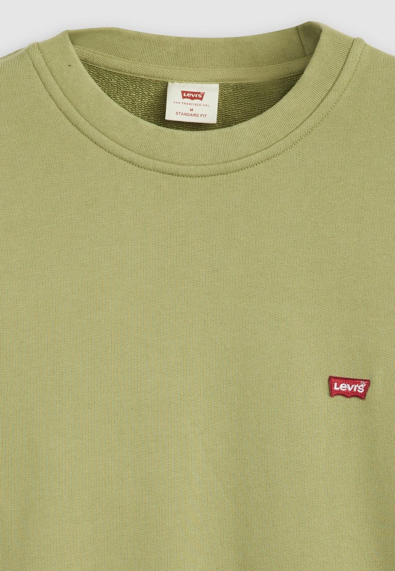 Grünes Baumwoll-T-Shirt mit geripptem Rundhalsausschnitt und kleinem roten Levi's-Logo-Patch. Textilart, weicher Stoff in einem Standard-Fit-Design.