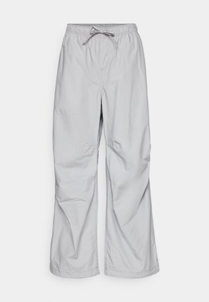 Pantalon décontracté gris clair avec ceinture élastique et cordon, jambes droites et légers plis sur le tissu.