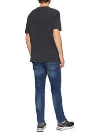 Zwarte katoenen t-shirt met korte mouwen, casual pasvorm. Gekleed met blauwe denim jeans en zwarte sport schoenen met witte zolen.
