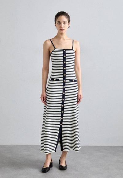 Robe sans manches rayée en ivoire et bleu marine, avec un devant à boutons, deux poches et une texture ribbée, atteignant le milieu du mollet.