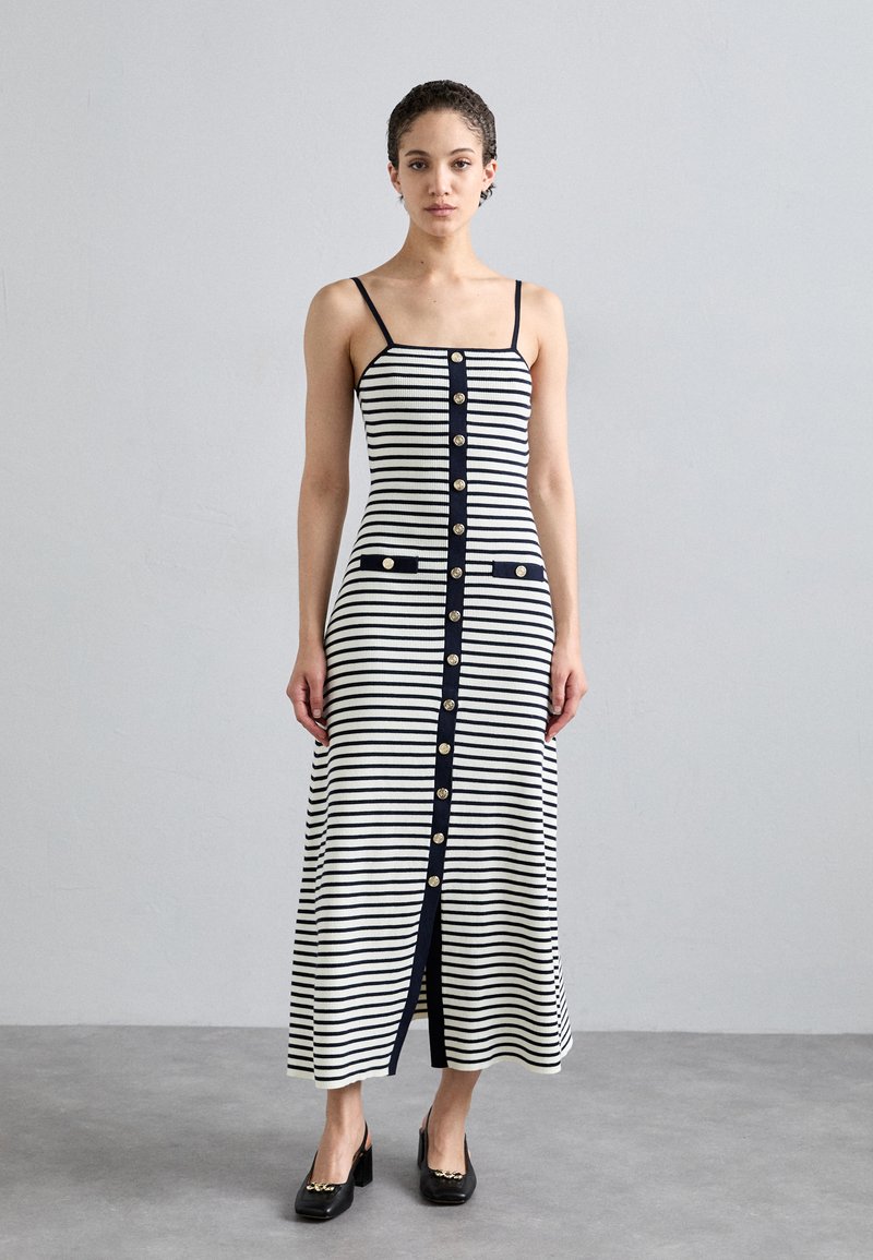 Gestreiftes ärmelloses Kleid in Elfenbein und Marineblau, mit Knopfleiste, zwei Taschen und gerippter Textur, das bis zur Mitte der Wade reicht.