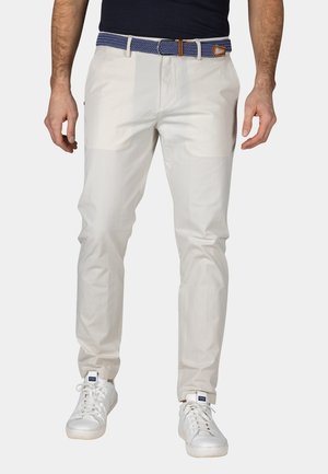 Witte katoenen broeken met een rechte pasvorm, voorzien van een blauwe patroonriem en bruine leren accenten, gecombineerd met witte sneakers.