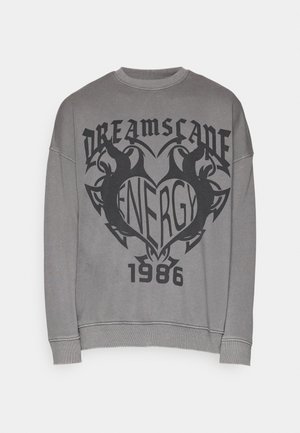 Sweatshirt gris avec encolure ronde, épaules tombantes, et un design imprimé présentant du texte stylisé et des graphiques en noir. Accentué par des poignets côtelés.