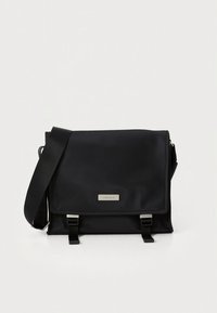 Mustast nailonist valmistatud õlakott, millel on sile tekstuur, klapiga sulgur, kaks pannalefekti ja reguleeritav rihm.