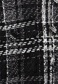 Tissu tissé noir et blanc avec un motif à carreaux dense et une texture de couture visible, montrant les détails du bouton et de la poche.