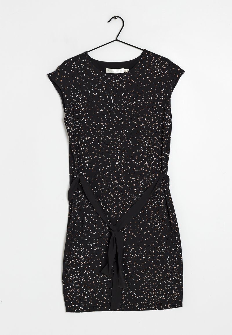Vestido negro con un patrón floral en blanco y melocotón. Mangas cortas, cinturilla con lazo y tela suave. Está colgado en una percha negra.