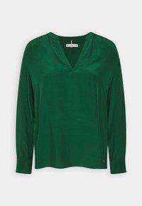 Zielona bluzka z długim rękawem i dekoltem w serek, wykonana z gładkiego materiału. Posiada marszczone ramiona oraz luźny krój. Prosty design bez wzorów.