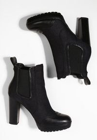 Botines negros con una mezcla de cuero suave y tejido texturizado, con un tacón alto y paneles laterales elásticos para un fácil acceso.