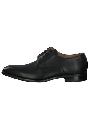 Chaussure habillée en cuir noir avec un bout pointu, des coutures discrètes et des lacets foncés. Présente un petit talon et un branding minimal sur le côté.