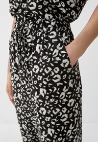 Pantalons à motifs noir et blanc avec une taille à cordon et des poches latérales, mettant en avant un tissu doux et une coupe ample.