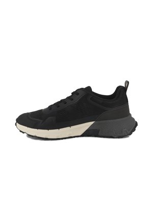 Chaussure de sport noire avec une tige en mesh et suède, une semelle intermédiaire blanche épaisse, une semelle extérieure en caoutchouc noir texturé, et une languette à l'arrière pour un enfilage facile.