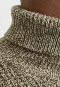 Sweter z wysokim kołnierzem w ziemistych odcieniach, posiadający prążkowaną strukturę. Tkanina zawiera mieszankę jasnych i ciemnych włókien.
