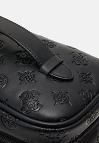 Black leather bag with embossed logo pattern, featuring a rounded shape and a top handle for carrying. Smooth texture and zip closure.