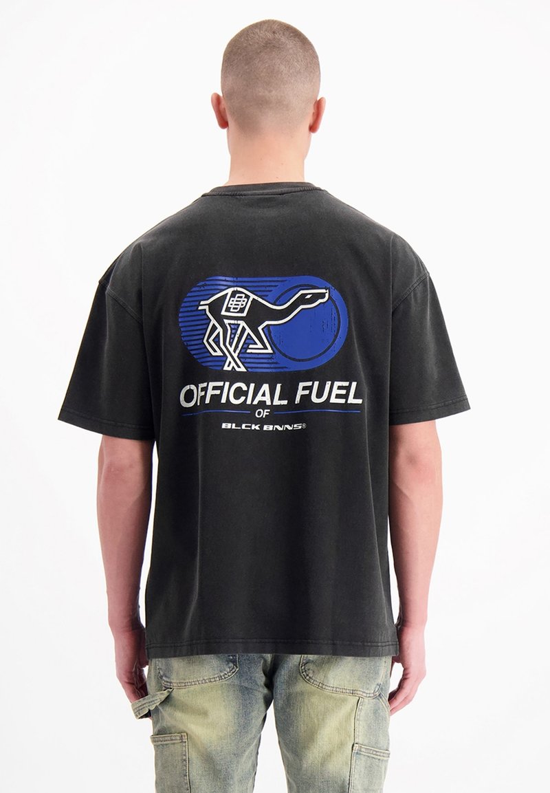 Zwarte oversized T-shirt met een dinosaurus graphic ontwerp in blauw en wit op de achterkant. Katoenen materiaal met korte mouwen en een ronde hals.