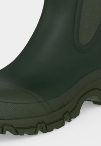 Σκούρο πράσινο λαστιχένιο αδιάβροχο μπότες με ανάγλυφη σόλα και ελαστική πλευρική επιφάνεια για εύκολη χρήση.